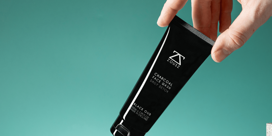 A hand holding the face wash over some stone