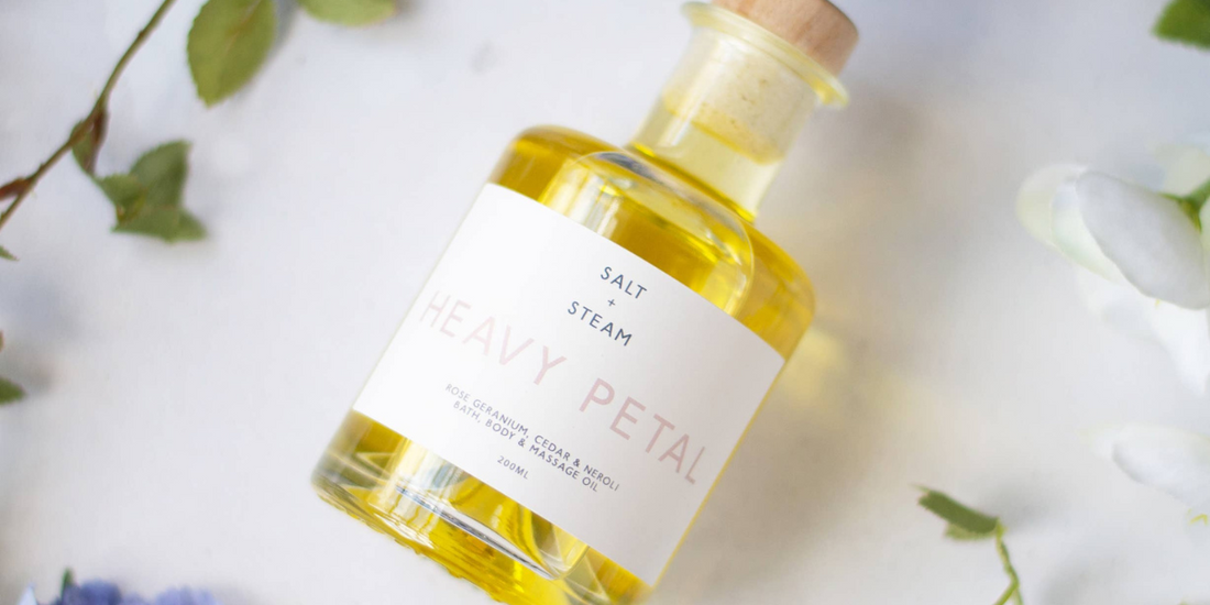 Bottle of Floral Body, Bath and massage Oil on a cloth with flowers around it.