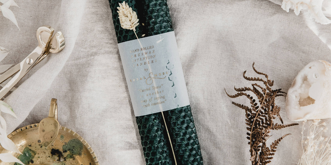 Moss Green candles laid on a cloth with a candle holder to the side and a candle stub.
