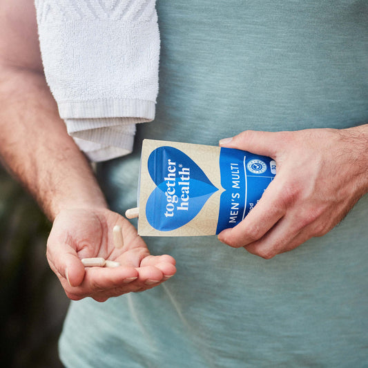 Man with a green shirt and sweat towel shaking tablets out of packet and into his hand.