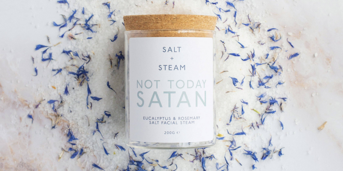 Jar of facial steam on a bed of the ingredients on a table.