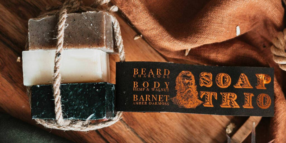Trio of soap with tag laying on a table with cloth and leaves and rope.