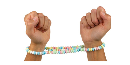 candy handcuffs on a set of hands on white background.