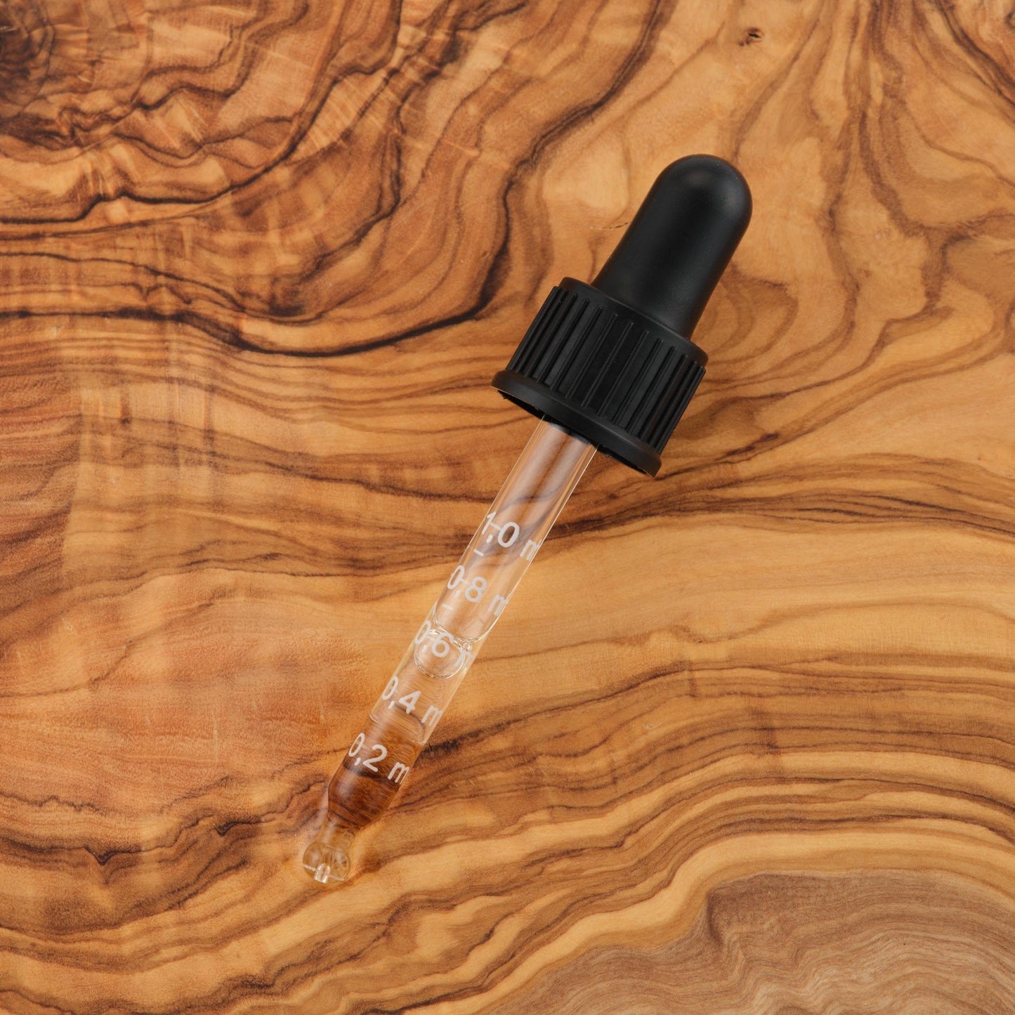 Clear dropper bottle with black cap on a wooden surface