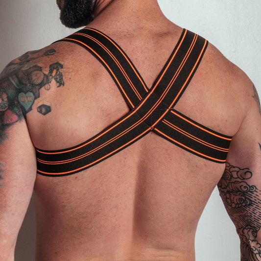 Person wearing black and orange sports bra with 'DEN' branding on a plain background