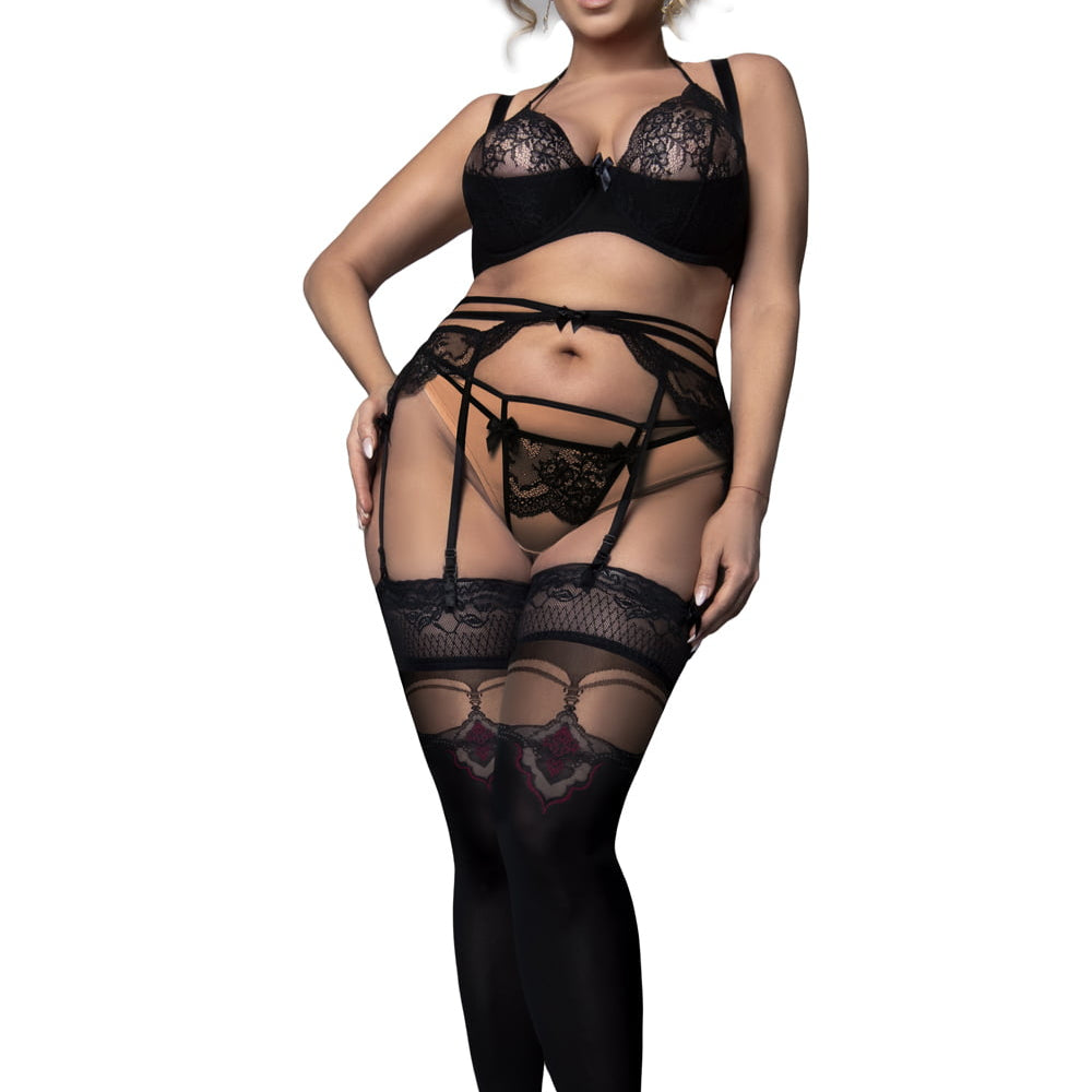 Lady wearing black lace holdups, with black bra on white background.