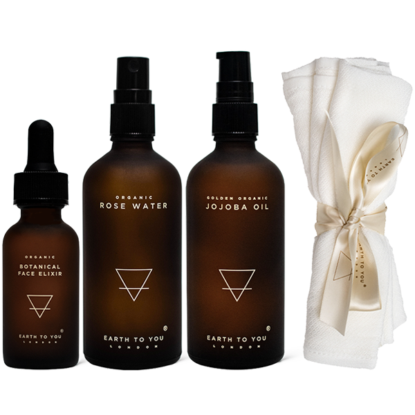 Set of Earth to You skincare products including a dropper, bottles with sprays, and a white towel on a white background.