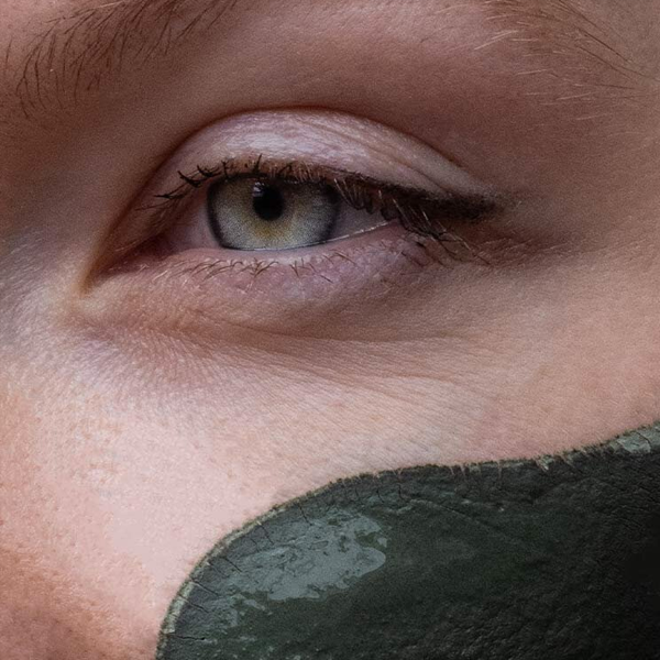 Close-up of a person's eye with a green face paint on the cheek