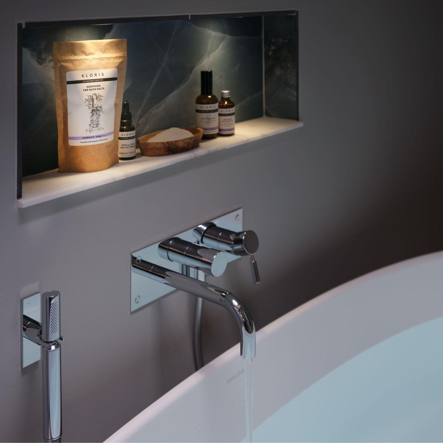 Bathroom setting with a faucet and toiletries on a shelf.