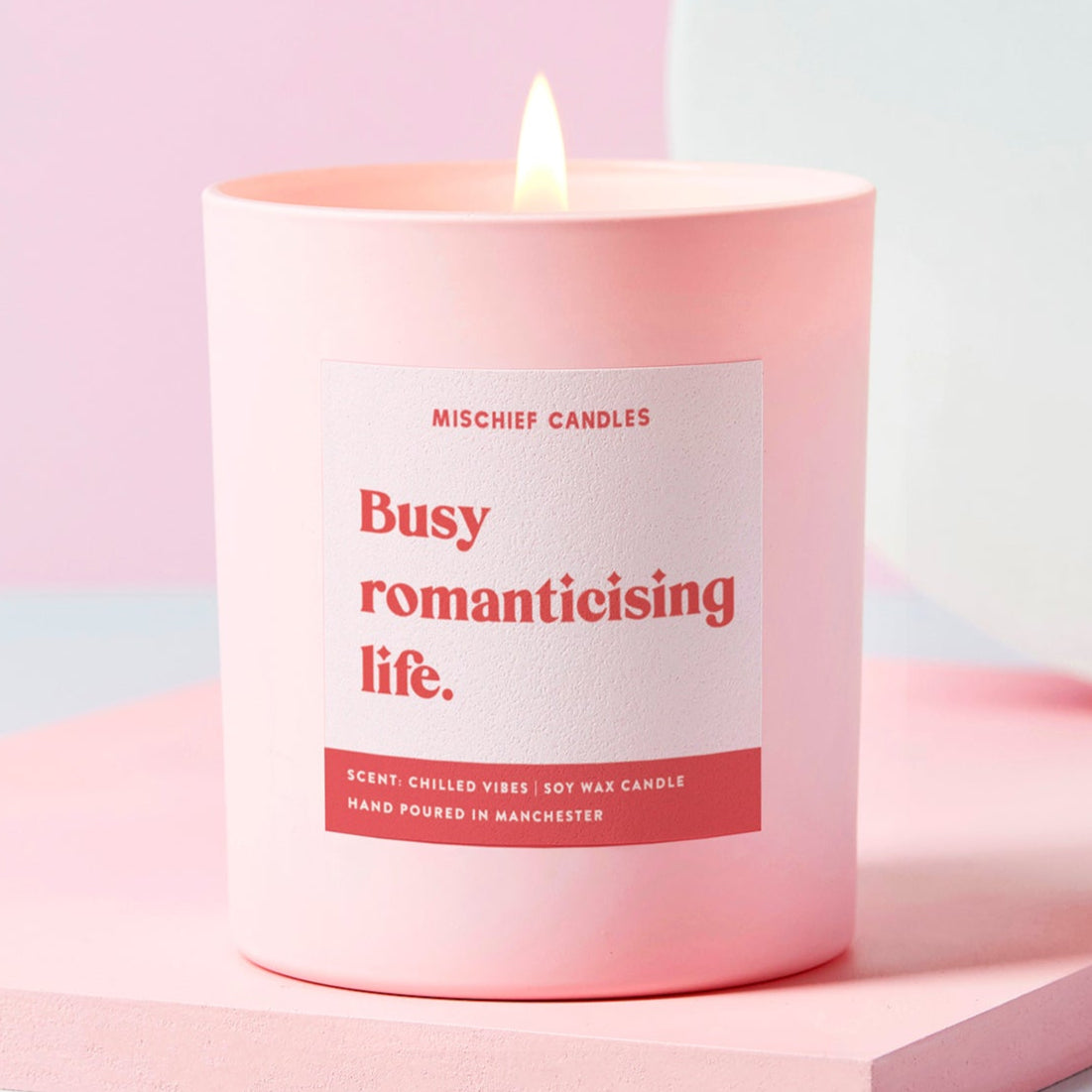 Pink candle with a label on a light pink background
