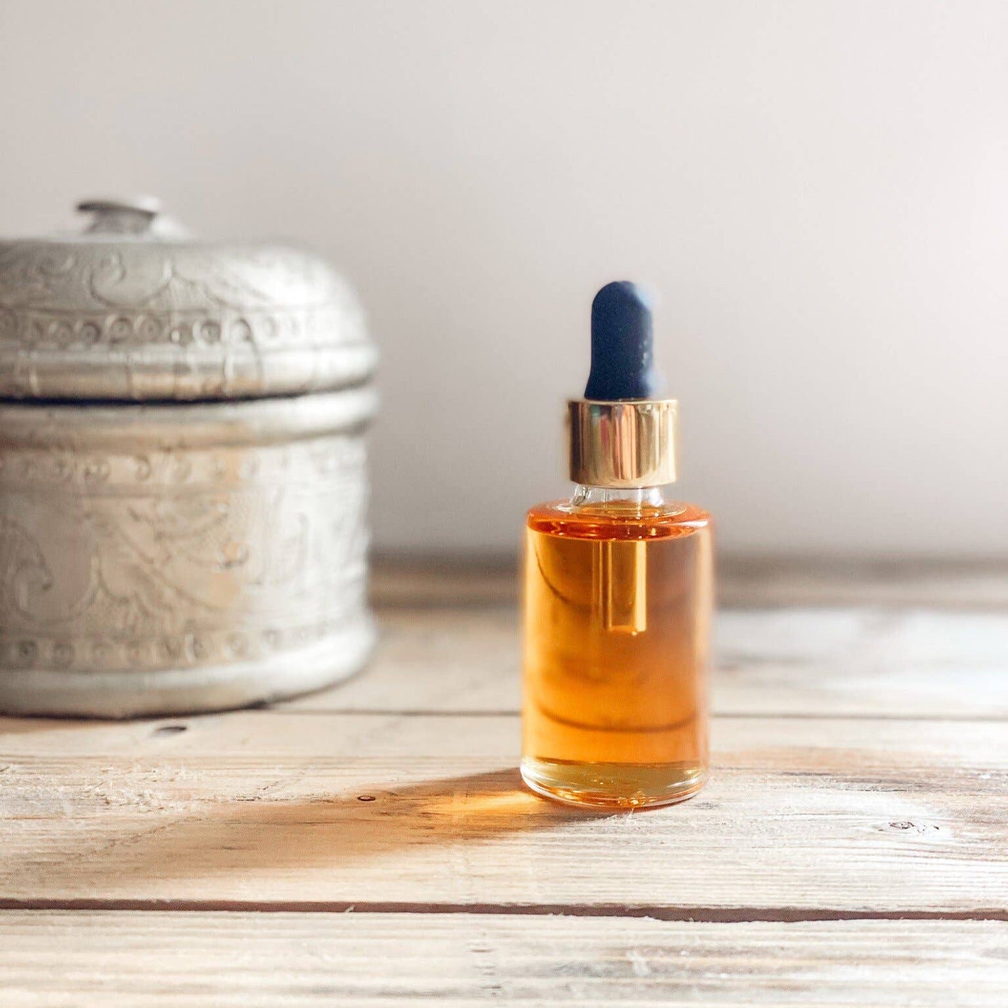 Bottle sitting on a wooden table with a pot in the background.