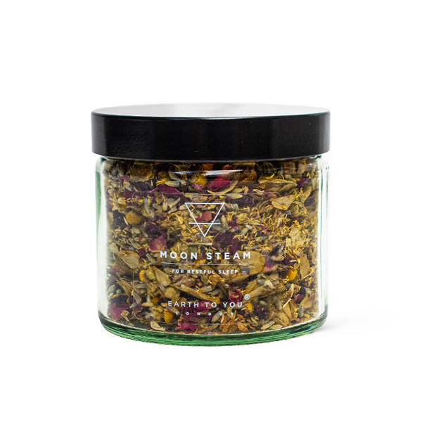 Glass jar with dried herbs labeled 'Moon Steam' on a white background
