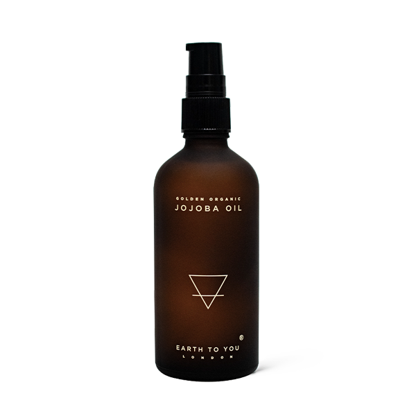 Brown bottle of Golden Organic Jojoba Oil with a black pump on a white background