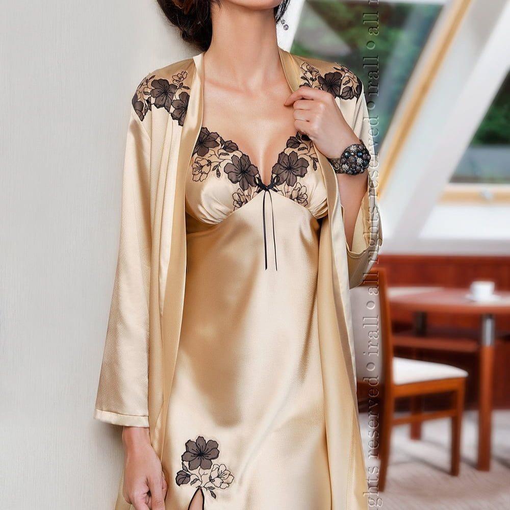 lady wearing a champagne nightdress in front of table and chairs and window.