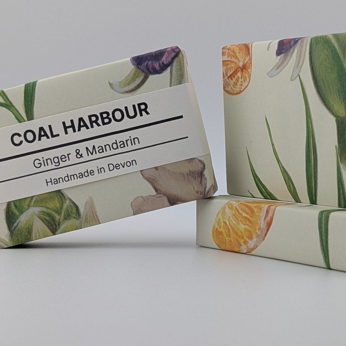 Two bars of soap with floral designs and a label for 'Coal Harbour' on a gray background