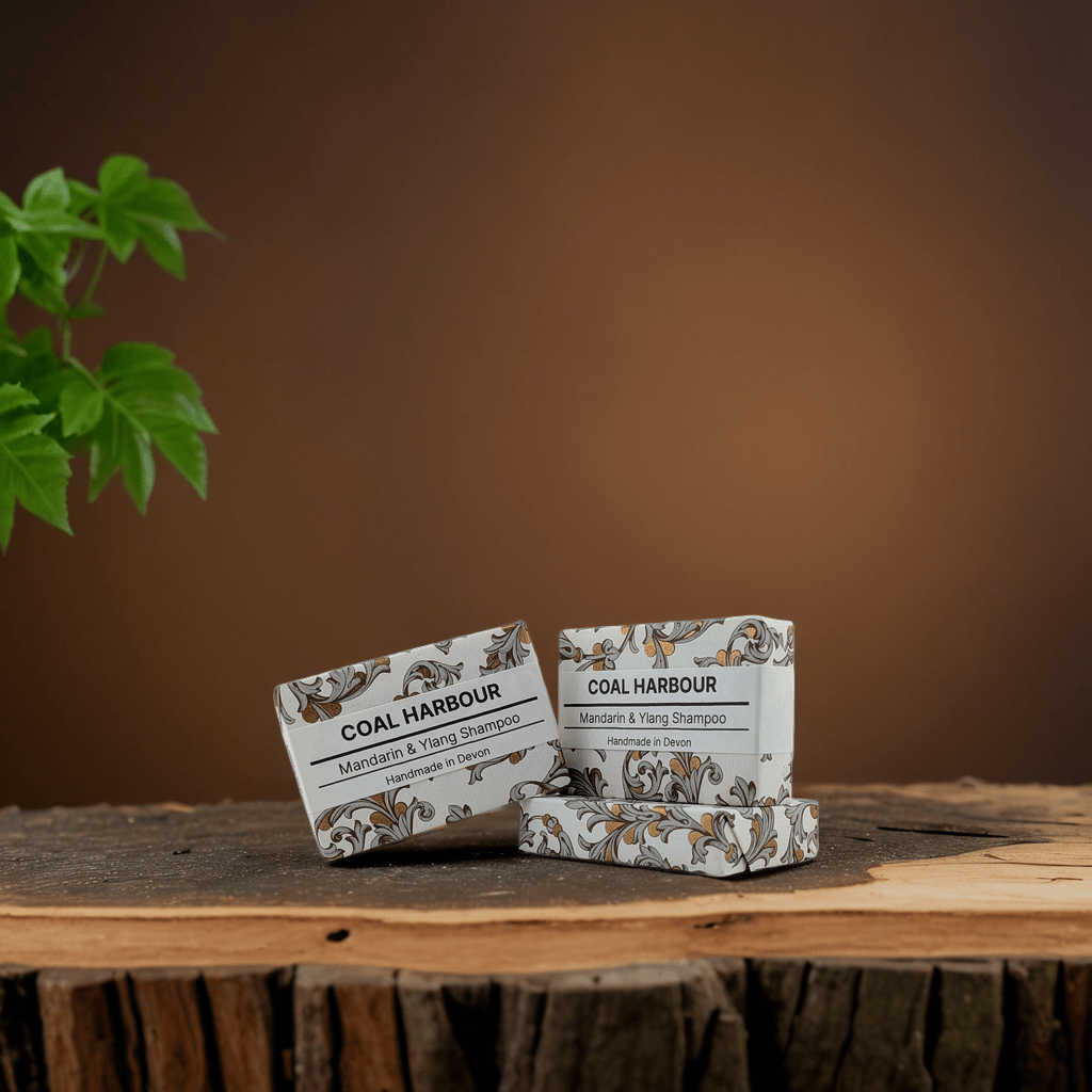 Three bars of Coal Harbour soap on a wooden surface with a plant in the background