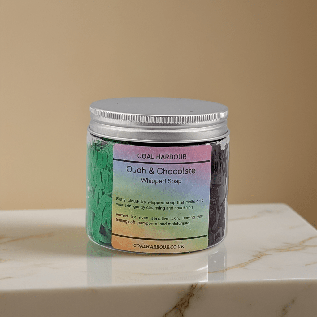 Jar of Coal Harbour Oudh & Chocolate Whipped Soap on a marble surface with a beige background
