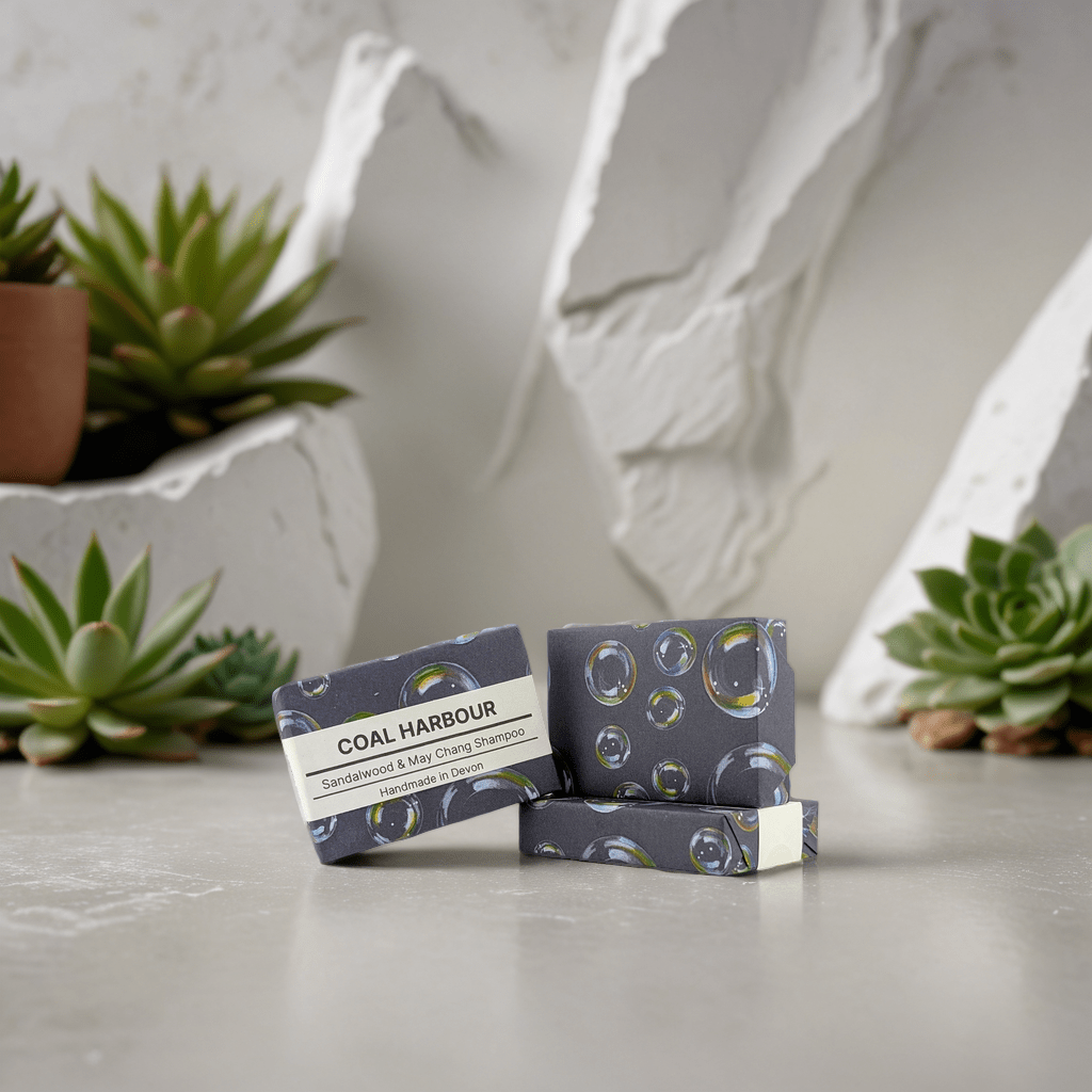 Three bars of Coal Harbour soap on a gray surface with succulents in the background