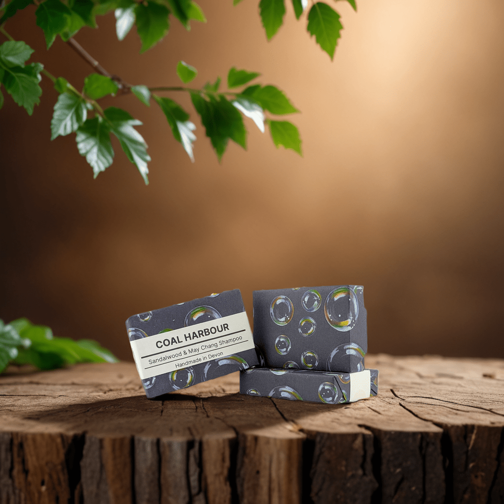 Two bars of Coal Harbour soap on a wooden surface with a blurred natural background