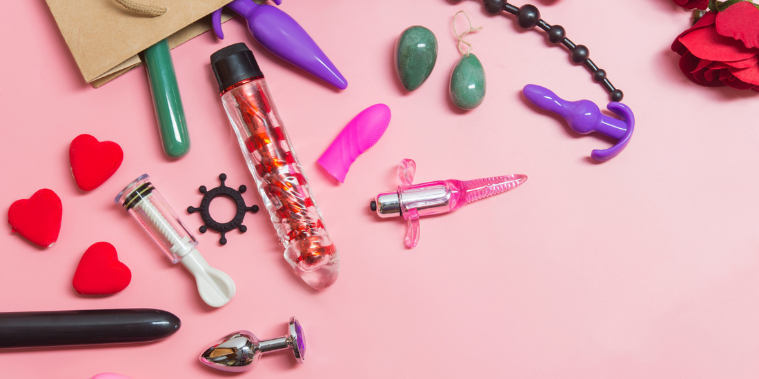 Range of sex toys on pink background with a rose