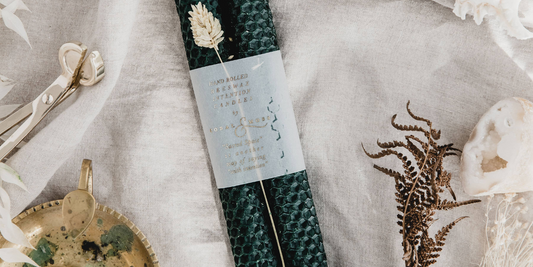 Moss Green candles laid on a cloth with a candle holder to the side and a candle stub.