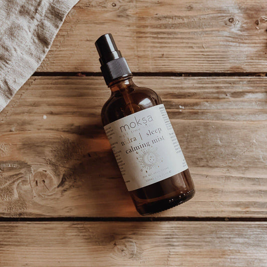 Bottle laying down on a wooden table with some cloth to the side.