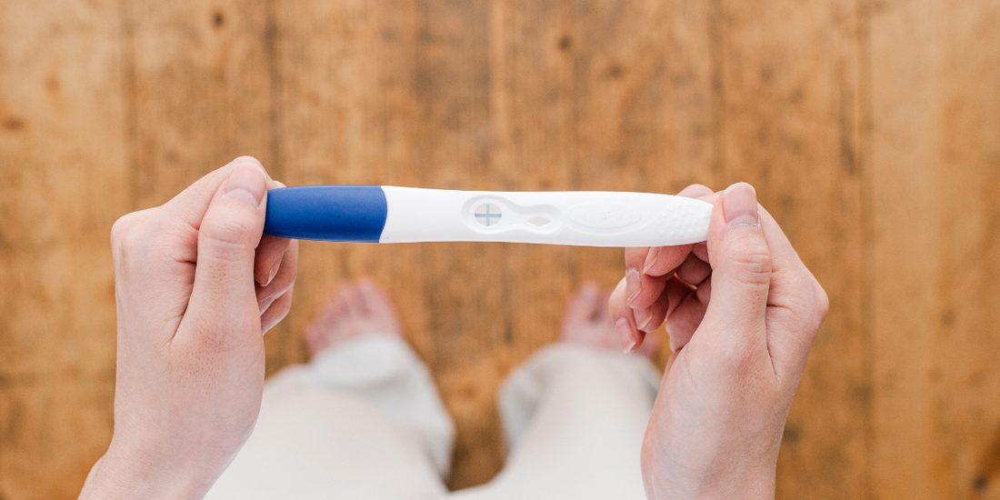 Image of a pregnancy test being held by a pair of hands.
