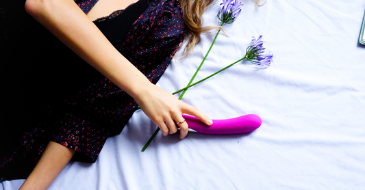 lady laying on a bed holding a vibrator