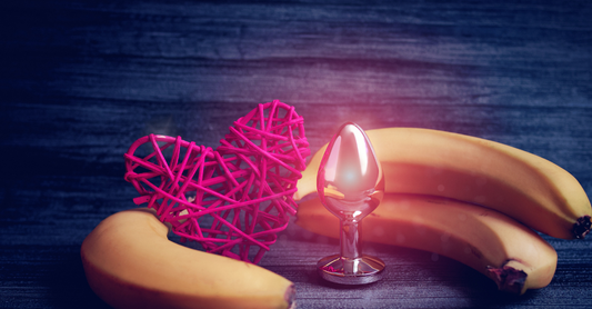 heart decoration with a butt plug and bananas on a blue wooden background