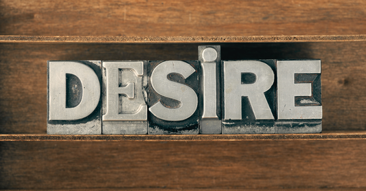 the word desire in typewriter buttons on a wooden background.