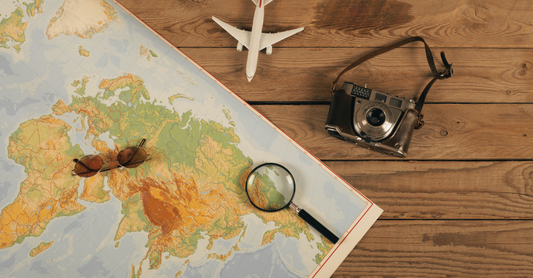 plane, camera, magnifying glass and map on a table