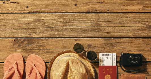 wooden background, with travel essentials like hat, glasses and passport