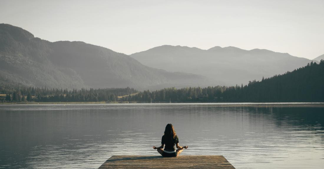 Lady meditating on a pier on a lake