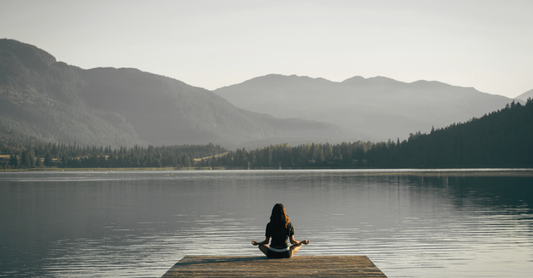 Lady meditating on a pier on a lake