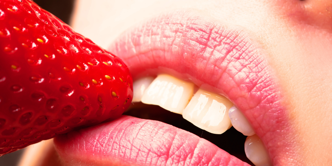 Women's lips touching a strawberry