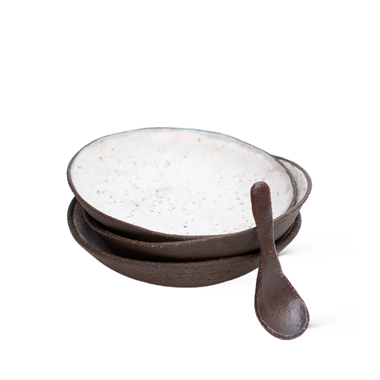 Set of ceramic bowls with a wooden spoon on a white background