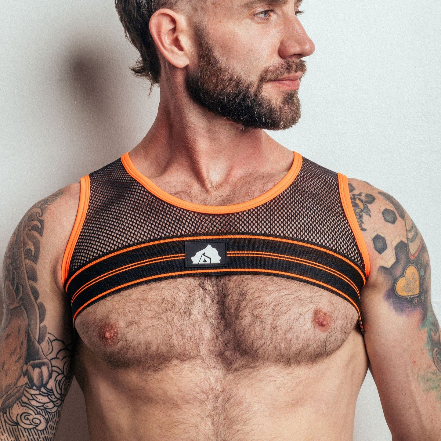 Man wearing a black and orange mesh tank top against a plain background