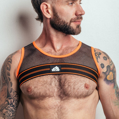 Man wearing a black and orange mesh tank top against a plain background