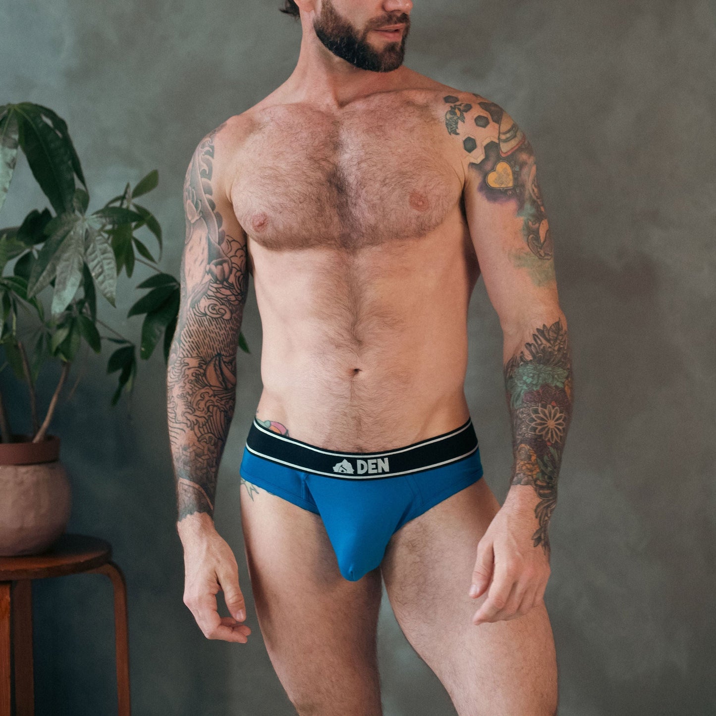 Man wearing a blue underwear with a brand logo against a gray background