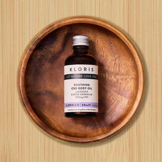 Bottle of KLORIS soothing CBD body oil on a wooden tray with a wooden background