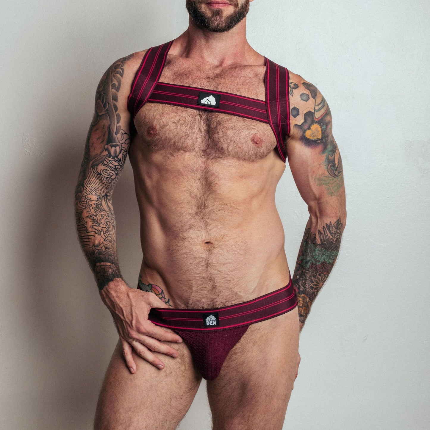 Man wearing a red Adidas sports bra and briefs against a plain background