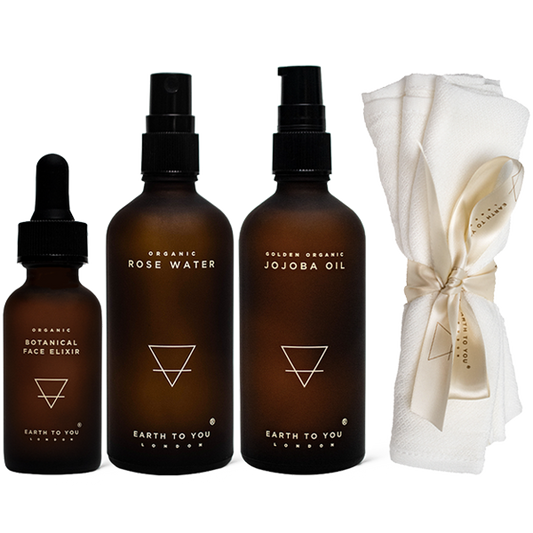 Set of Earth to You skincare products including a dropper, bottles with sprays, and a white towel on a white background.