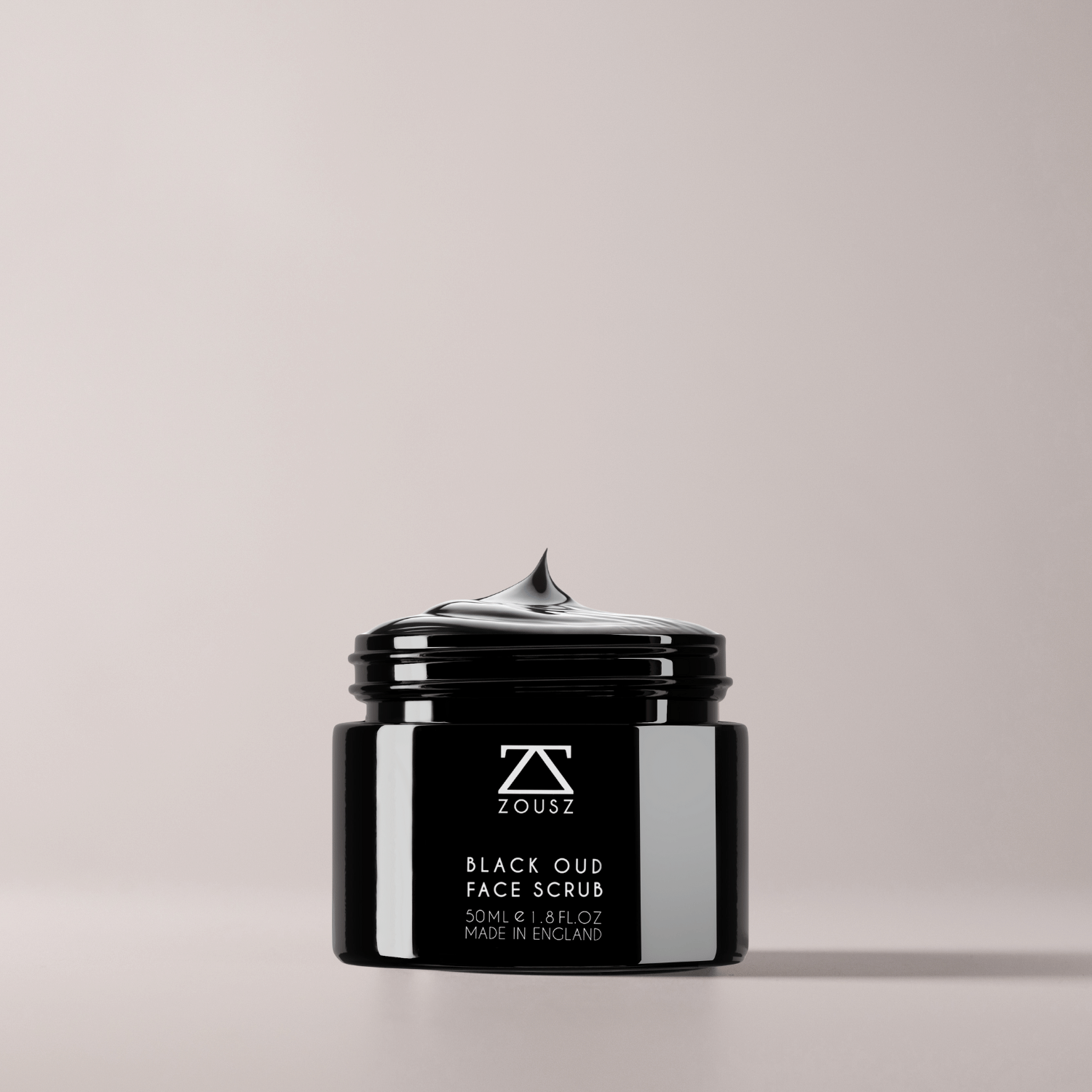 Black jar of ZOUSZ Black Oud Face Scrub on a light gray background