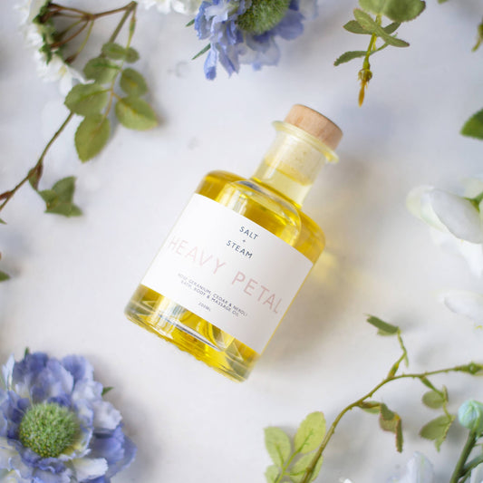 Bottle of Floral Body, Bath and massage Oil on a cloth with flowers around it.