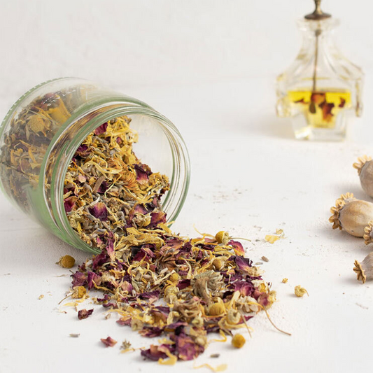 Glass jar with dried herbs on a white surface