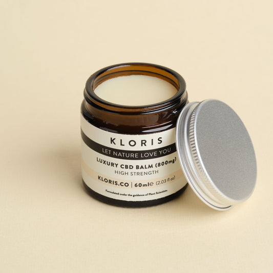 Kloris CBD balm jar with open lid on a beige background