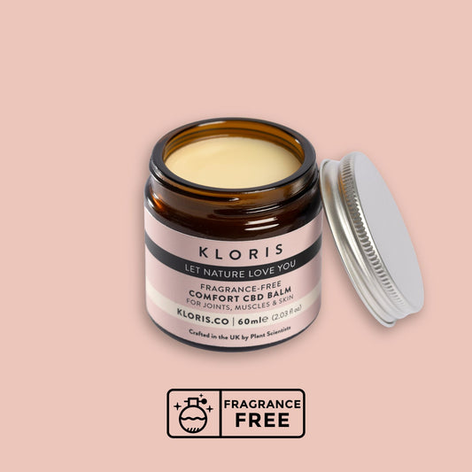 Kloris Comfort CBD Balm jar with open lid on a pink background