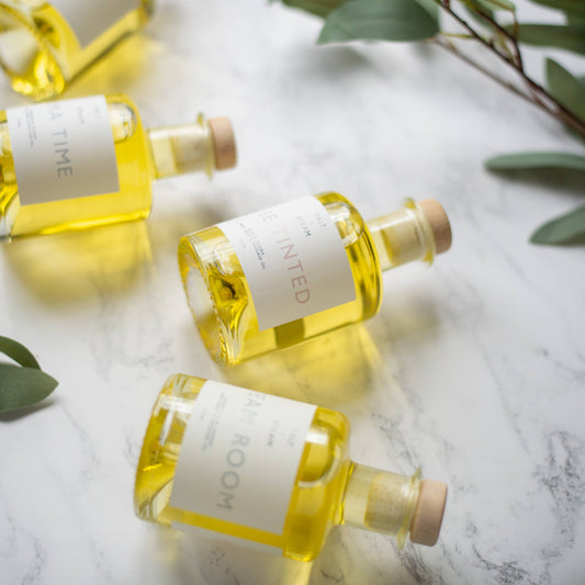 Multiple Bottles of oil laying on a table with leaves around them.
