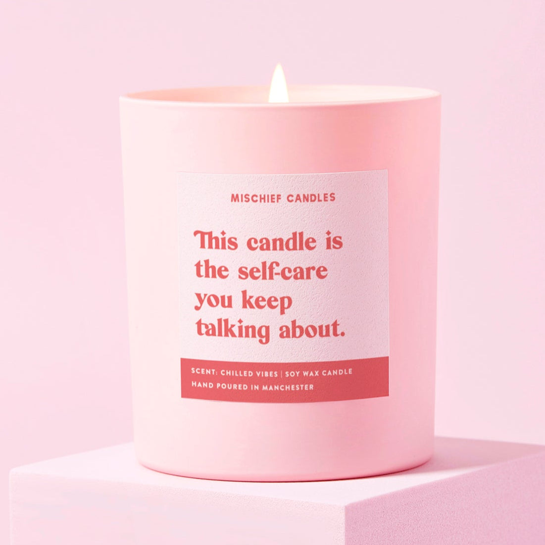 Pink candle with a label on a light pink background