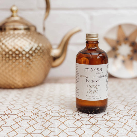 Bottle on a printed table, with a star plate and a gold kettle in the background.